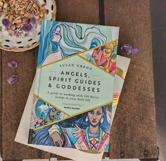 Book titled 'Angels, Spirit Guides & Goddesses' by Susan Gregg on a wooden surface with decorative elements.