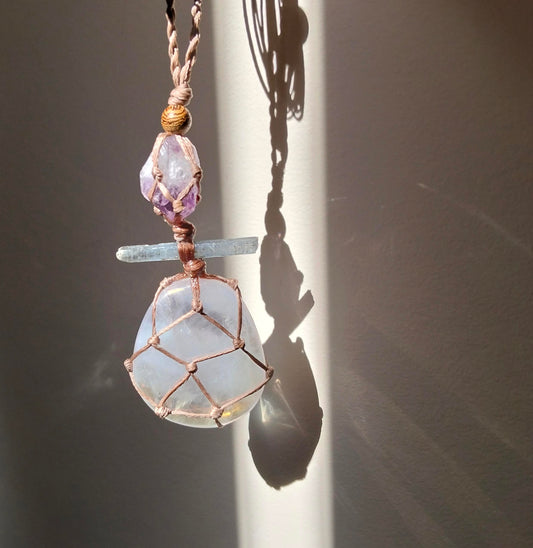 Necklace with a pendant featuring a large  rose aura quartz pendant smaller kyanite crystal amd amethyst gemstones with a hand made twisted leather chord