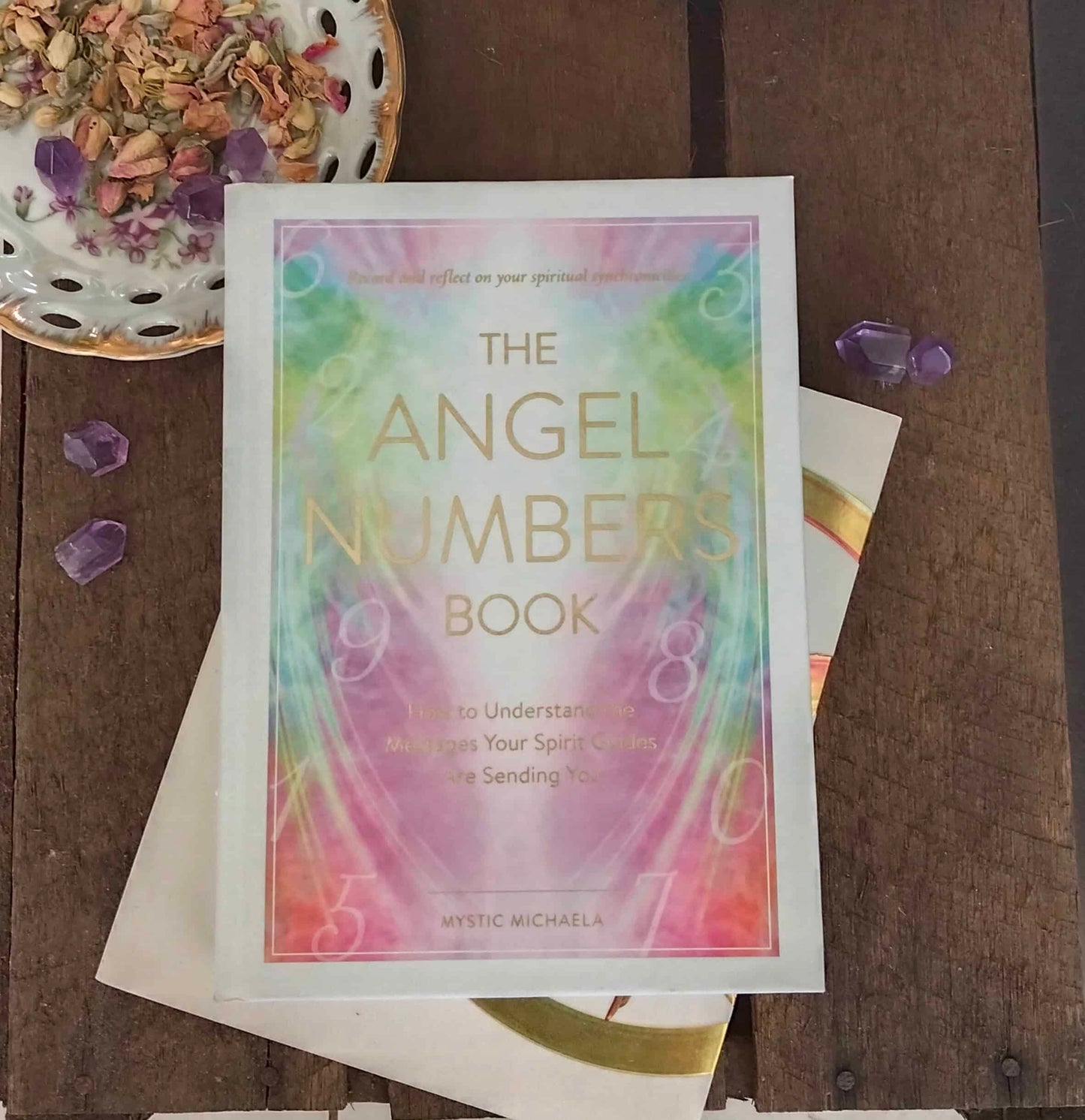 Book titled 'The Angel Numbers Book' on a wooden surface with decorative elements.
