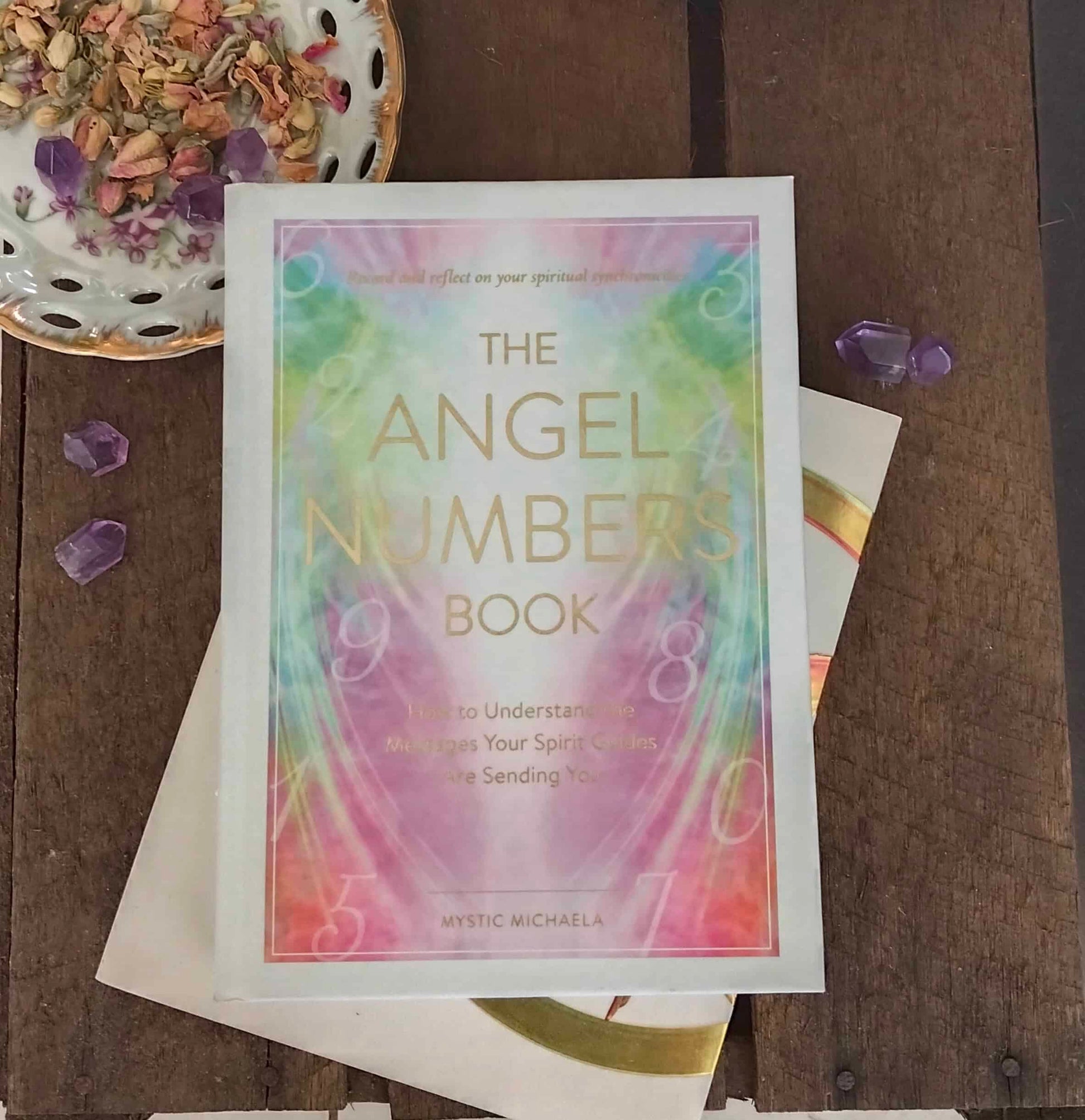 Book titled 'The Angel Numbers Book' on a wooden surface with decorative elements.